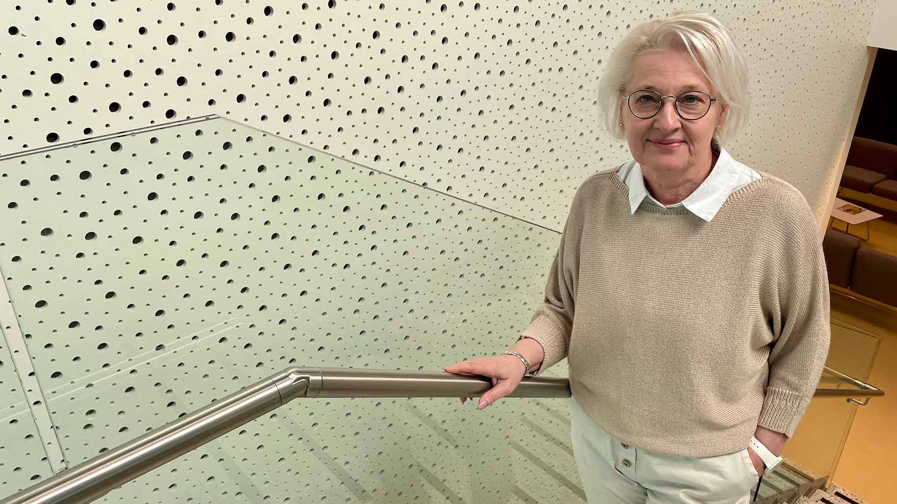 Nainen seisomassa rapussa, katsoo kameraan ja hymyilee.