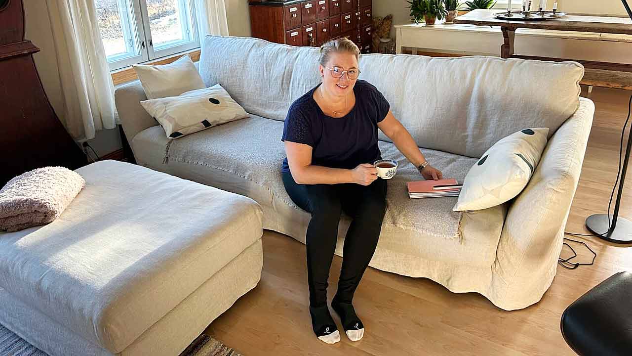 Sijaisäiti istuu sohvalla teekupin kanssa. 