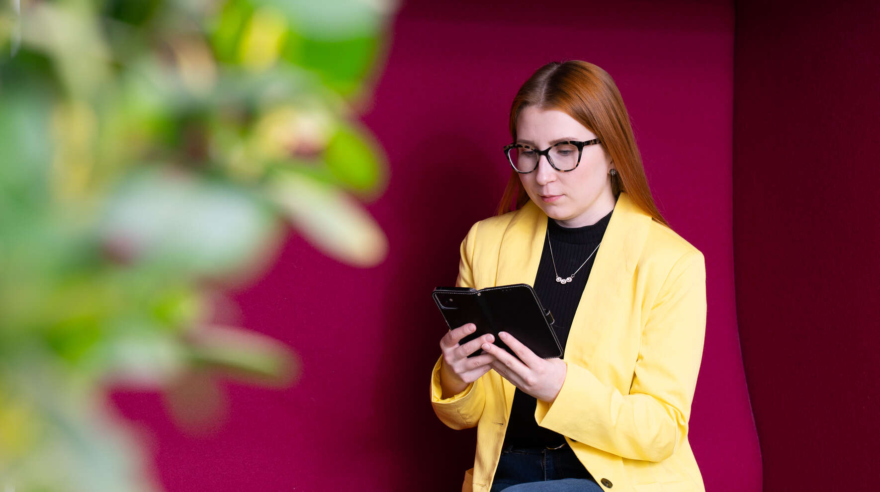 Nainen istuu sohvalla puhelin kädessään.