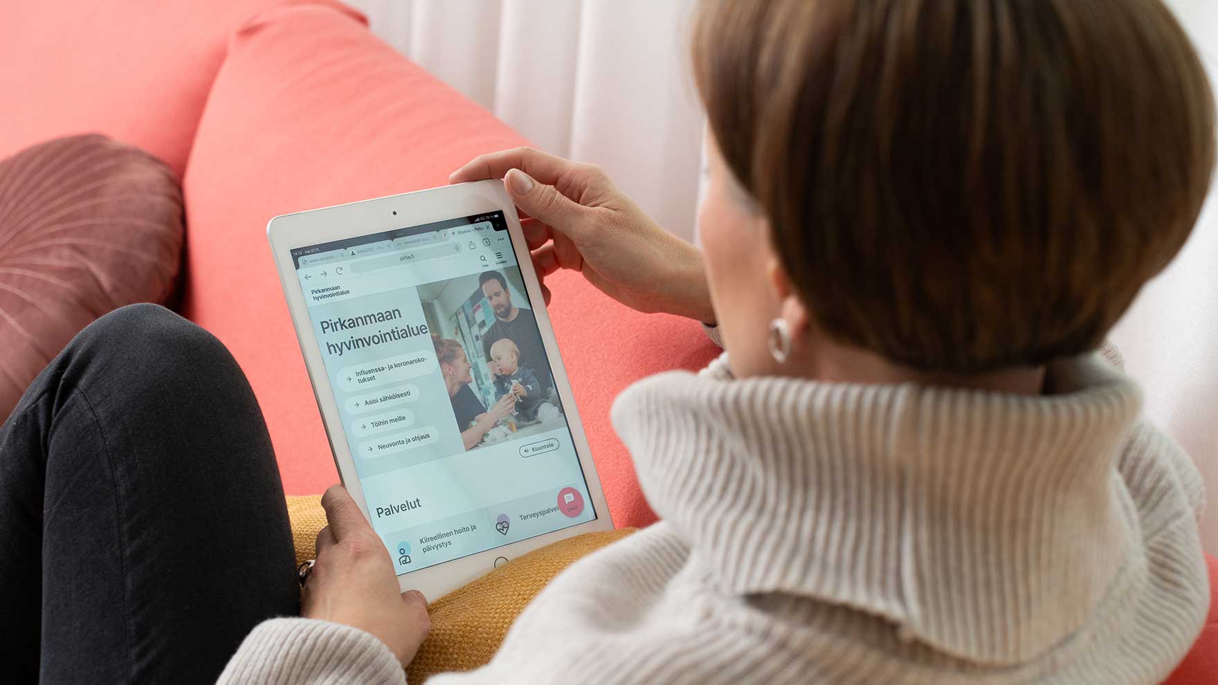 Nainen istuu sohvalla ja tutkii Pirha.fi-sivuja tabletilla.