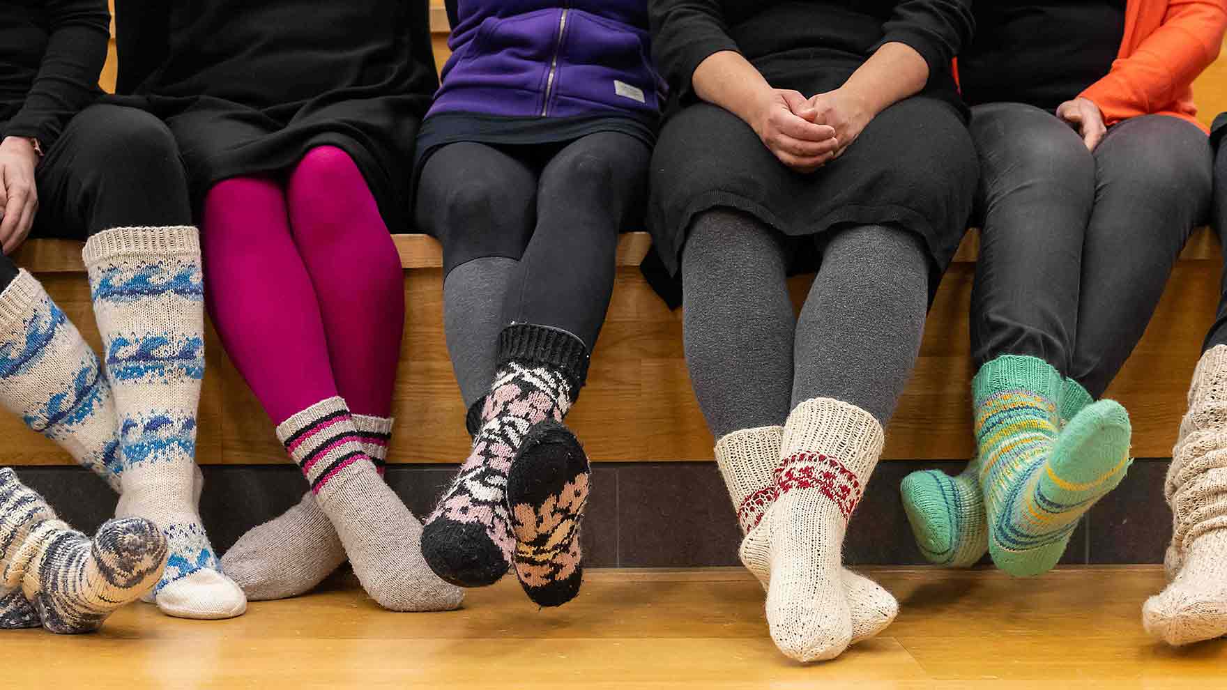 Istuvien ihmisten jalkoja, joissa on villasukkia.