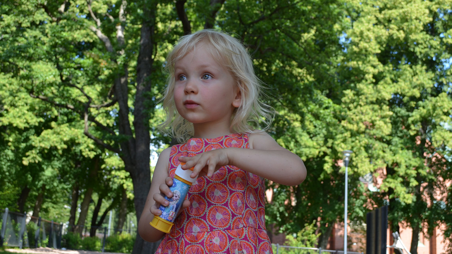 Tyttö puistossa kädessään saippuakuplapullo.