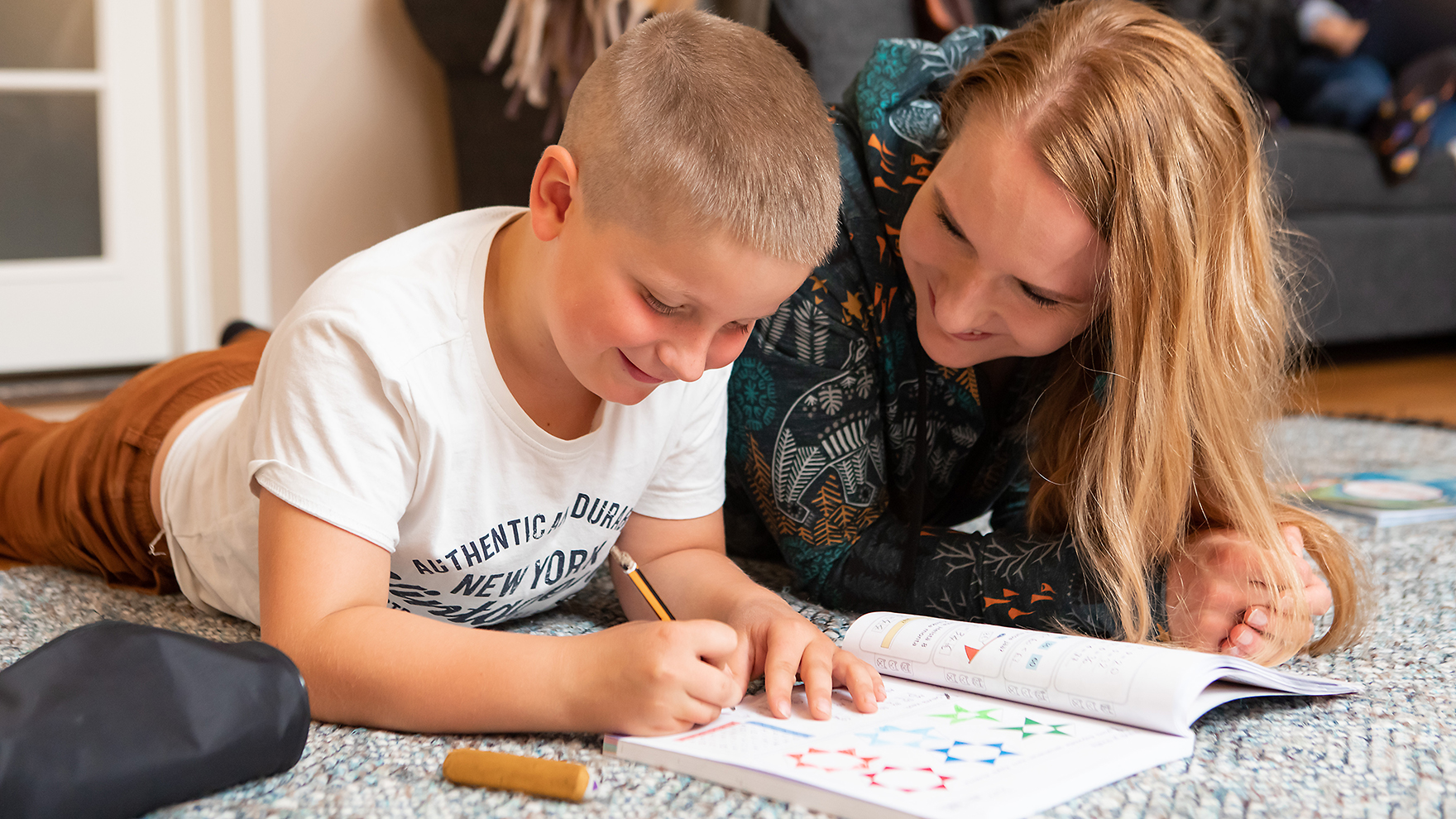 Lapsi ja aikuinen tekevät läksyjä yhdessä.