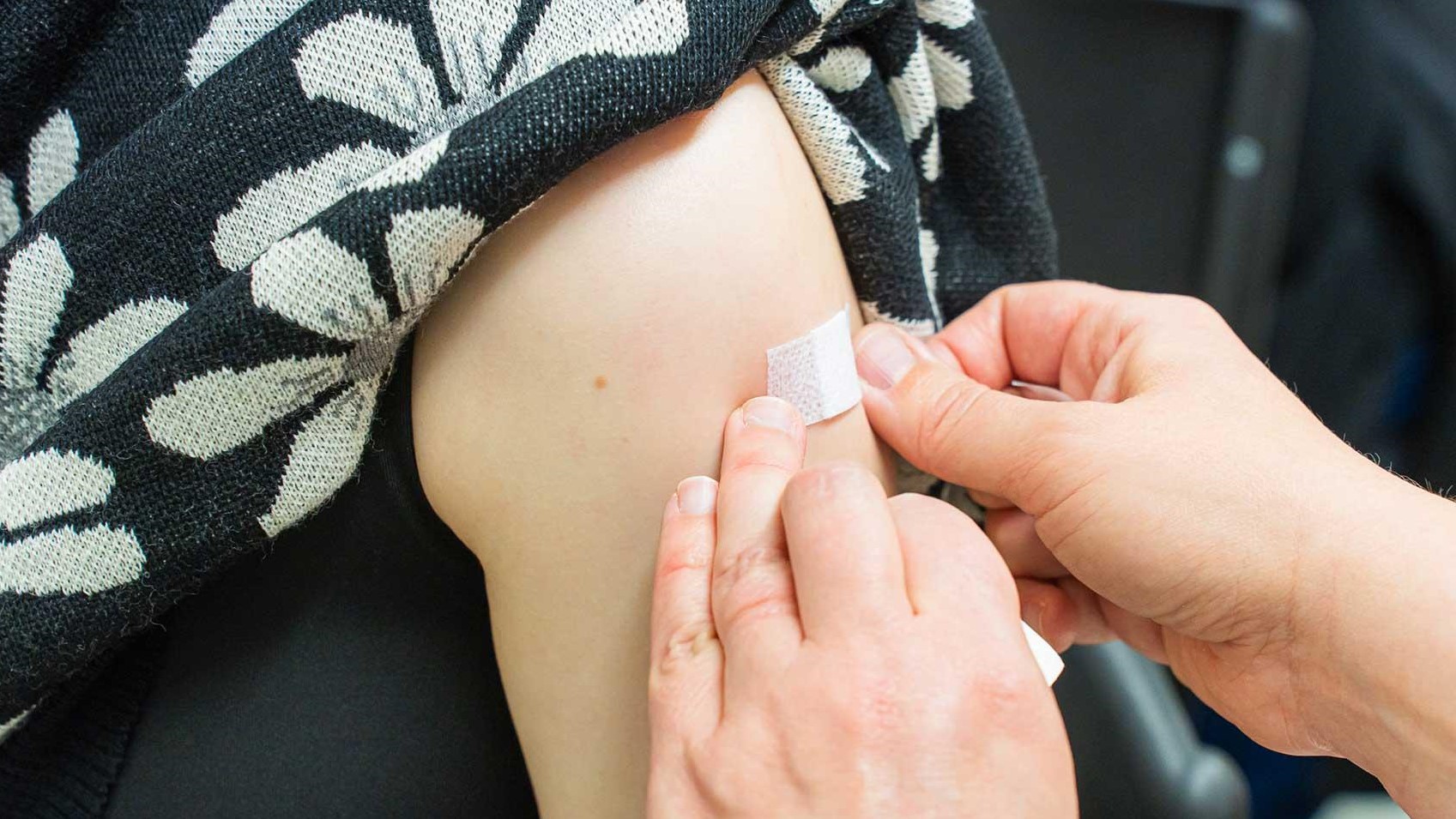 Naisen käsivarteen painetaan laastaria.