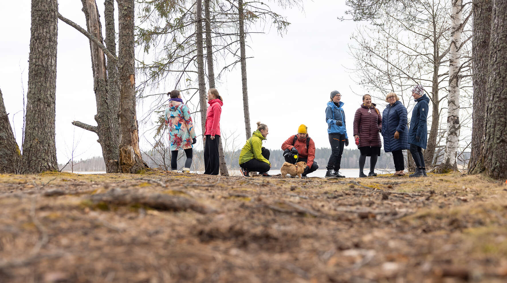 Ryhmä ihmisiä seisoo ulkoilualueen reunalla juttelemassa.