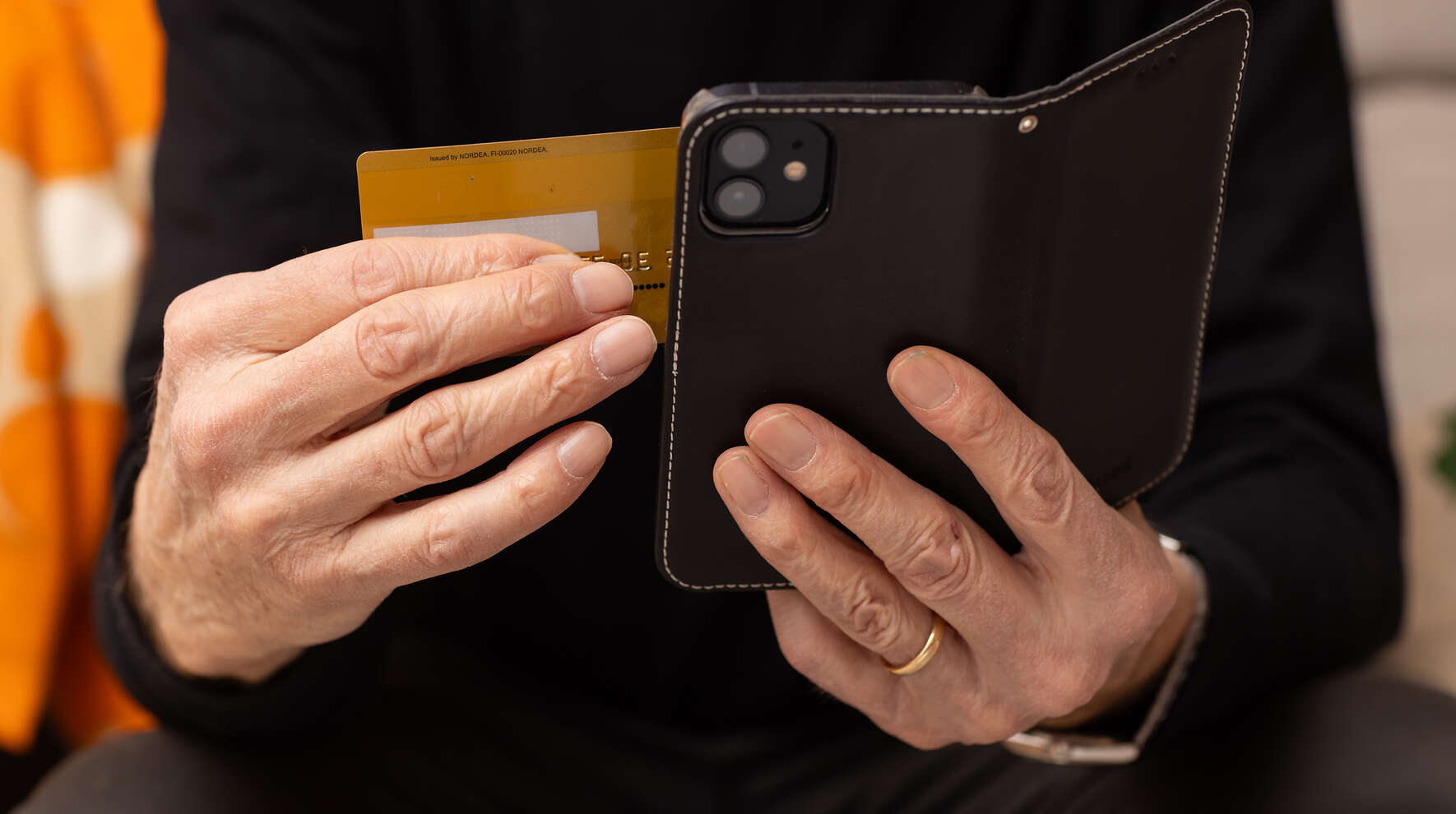 Pankkikortti ja puhelin kädessä.
