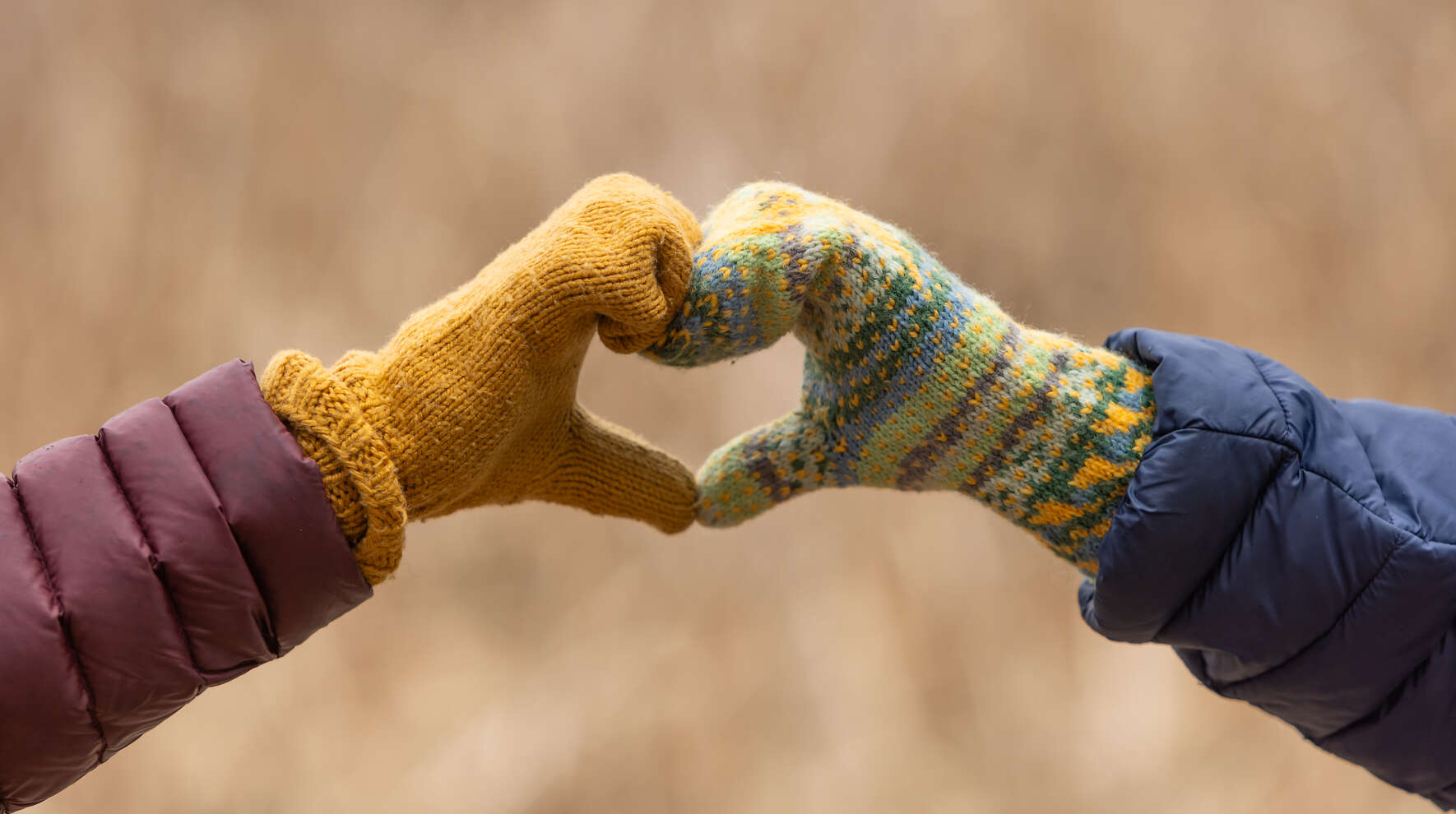 Kahden ihmisen lapasilla verhotut kädet, jotka muodostavat sydän-muodon.