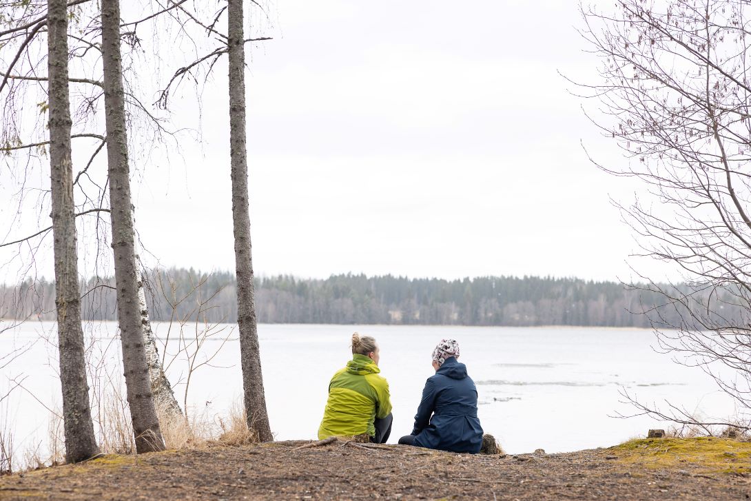 Kaksi henkilöä istuu rannalla.