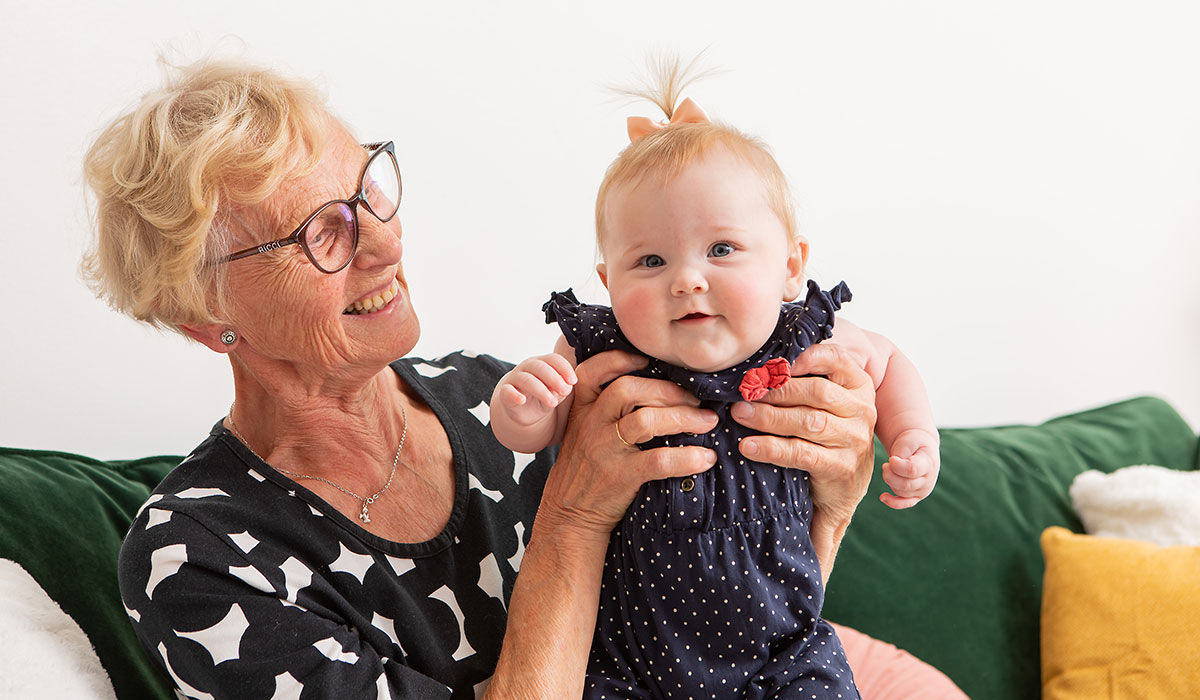 An elderly lady is holding a baby.