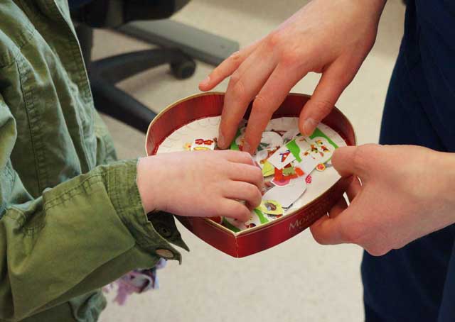 Tyttö valitsee tarran sydämenmuotoisesta laatikosta.