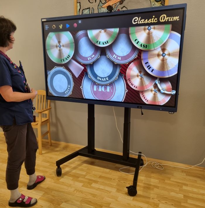 Clevertouch-laitteen vieressä Kirsi Vaittinen esittelee rumpusovellusta.