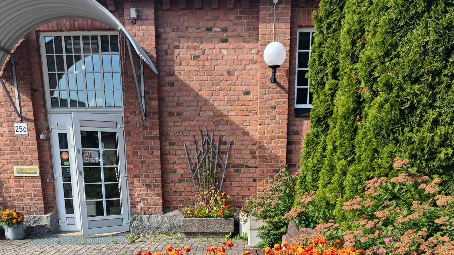 Punatillisen rakennuksen sisäänkäynti ja istutuksia