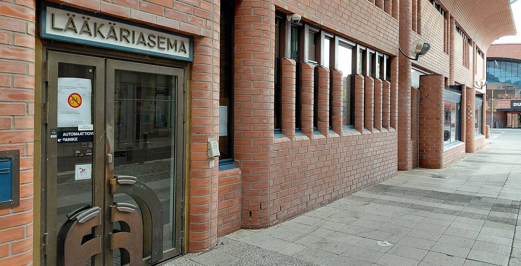 Punatiilisiä pyöreäkulmaisia rakennuksia ja sisäänkäynti, jossa lukee lääkäriasema.