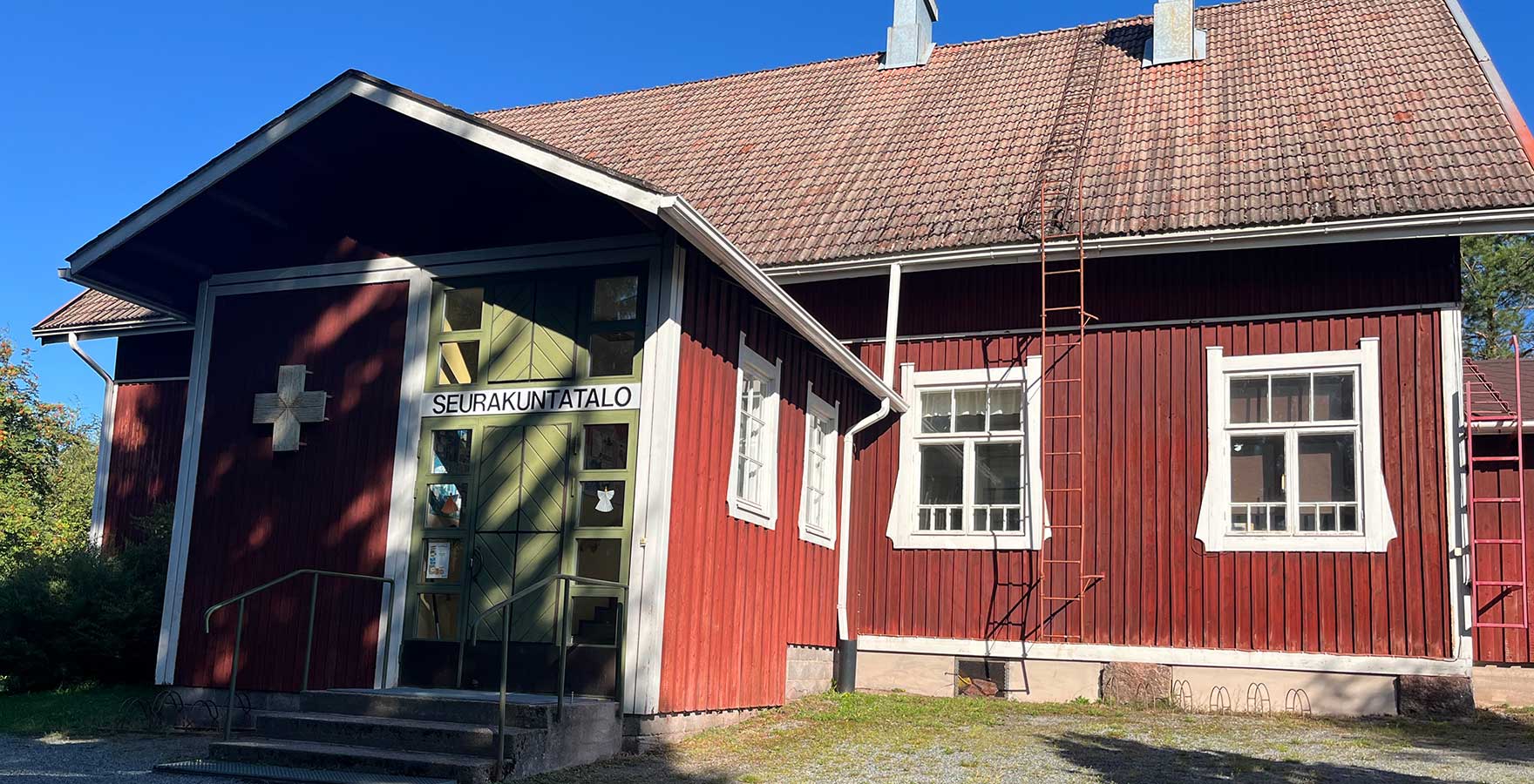 Punainen puutalo, jonka vihreässä ovessa lukee seurakuntatalo.