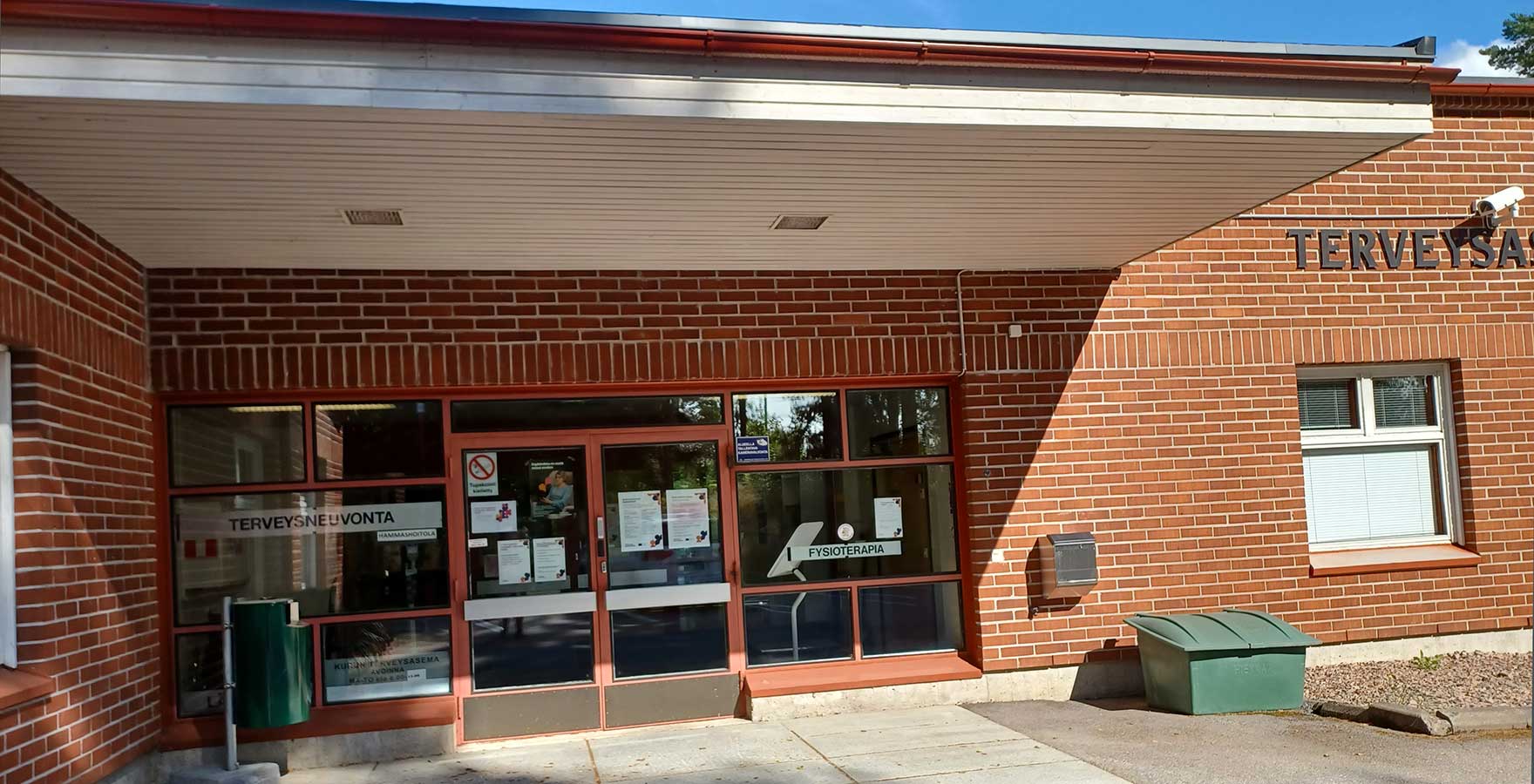 Punatiilisen rakennuksen siäänkänti. Seinässä lukee terveysasema.