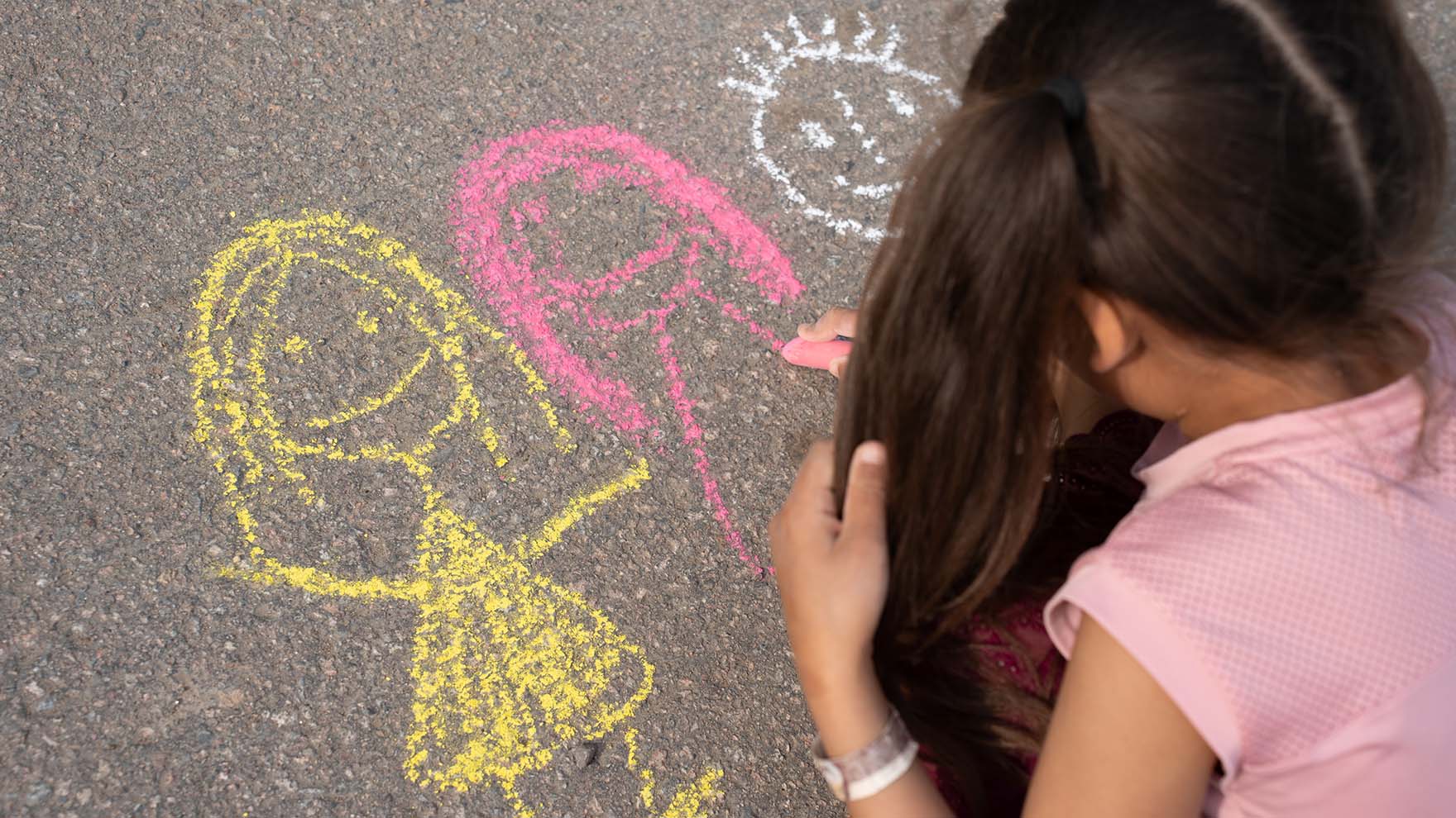Kuvituskuva lapsesta piirtämässä katuliiduilla.