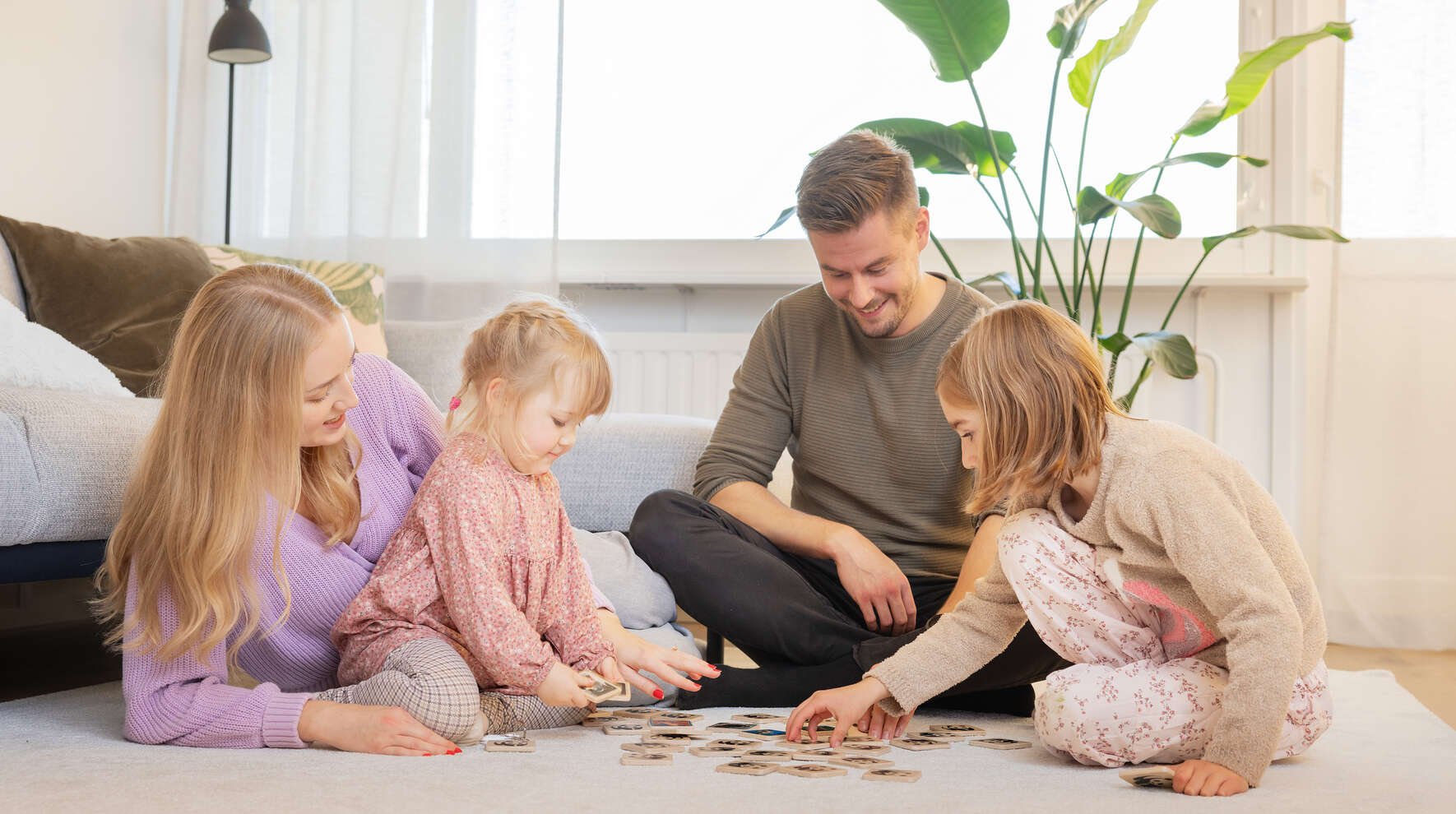 Perhe pelaa lattialla.