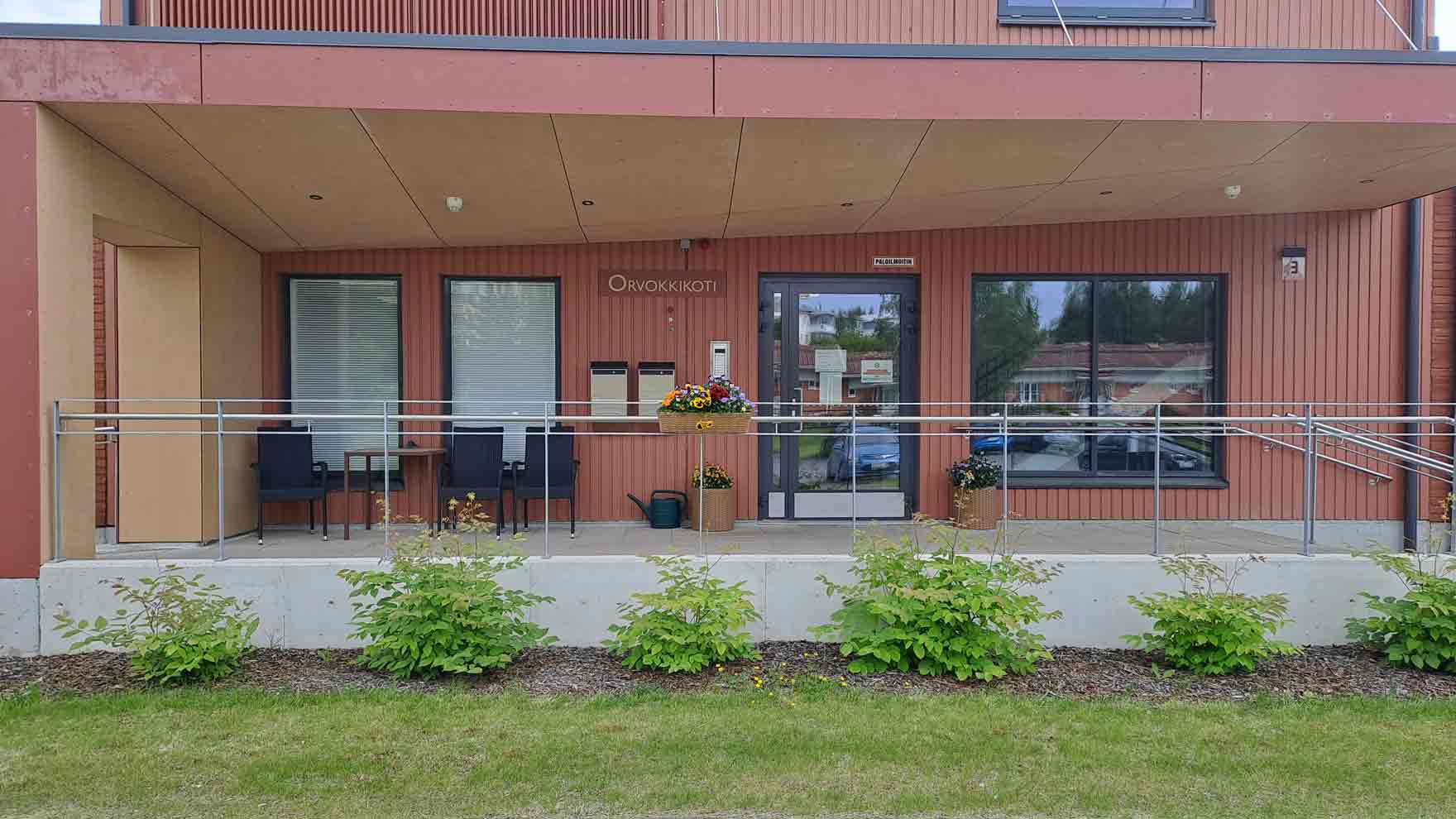 Punainen rakennus, jonka edessä istutuksia