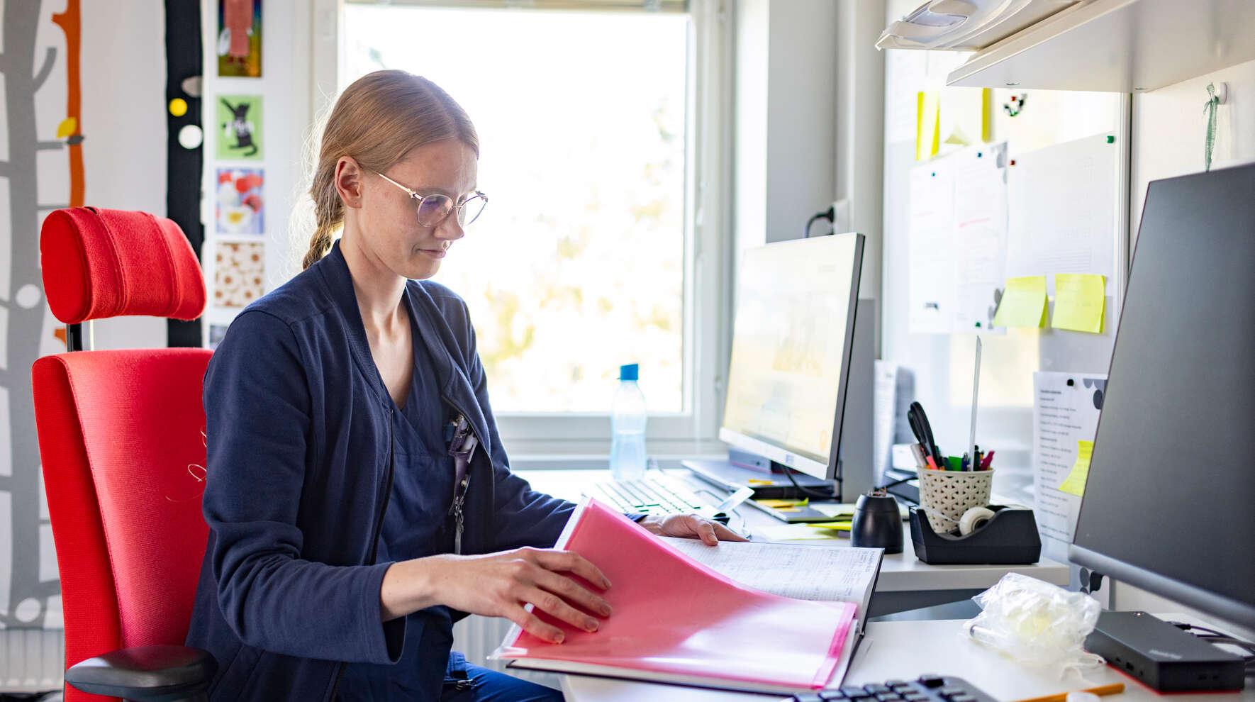 Karoliina Järvinen istuu toimistossa ja selaa papereita.