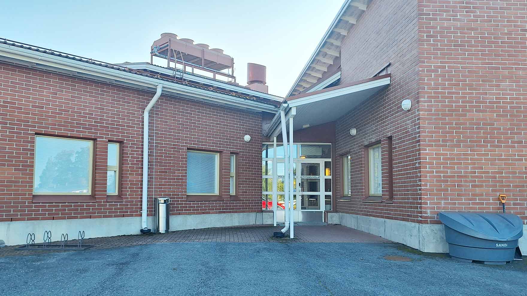 Sisäänkäynti V-kirjaimen muotoiseen yksikerroksiseen, punatiiliseen taloon.
