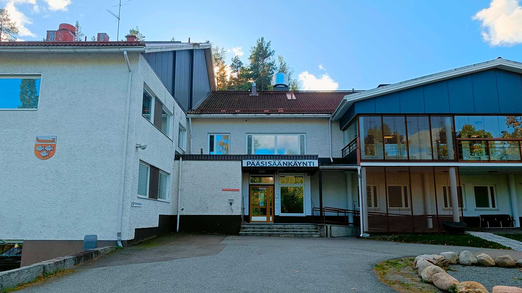 Vaalea, rapattu, kaksikerroksinen talo.