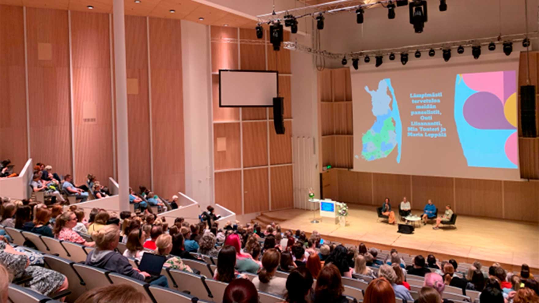 Valokuva Tampere-talon salista, jossa seurataan luentoa saattohoidosta.