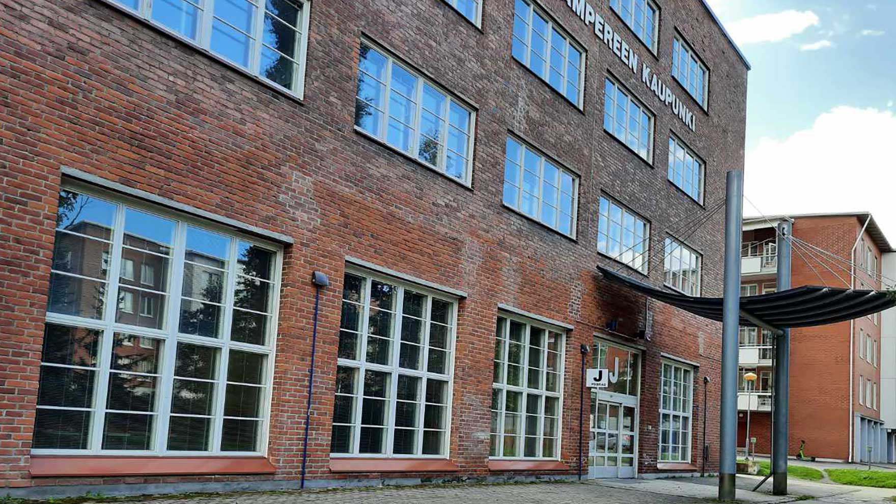 Punatiilinen Sarviksen kiinteistö, sisäänkäynti J-rappuun. Seinässä lukee Tampereen kaupunki.