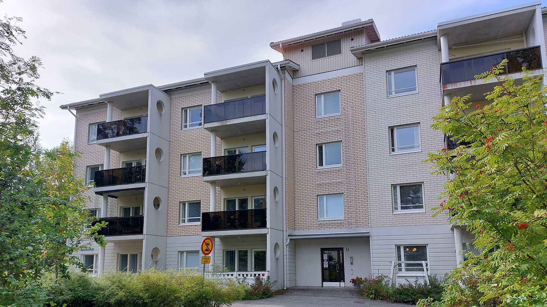 Nelikerroksinen kellertävä tiilikerrostalo.