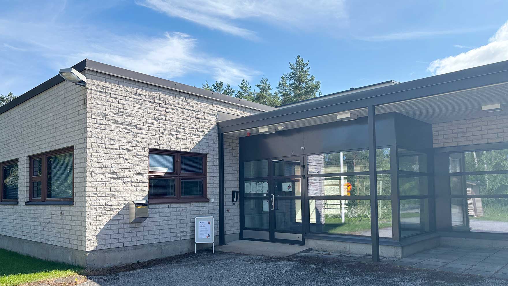 Matalan tiilirakennuksen lasinen sisäänkäynti.