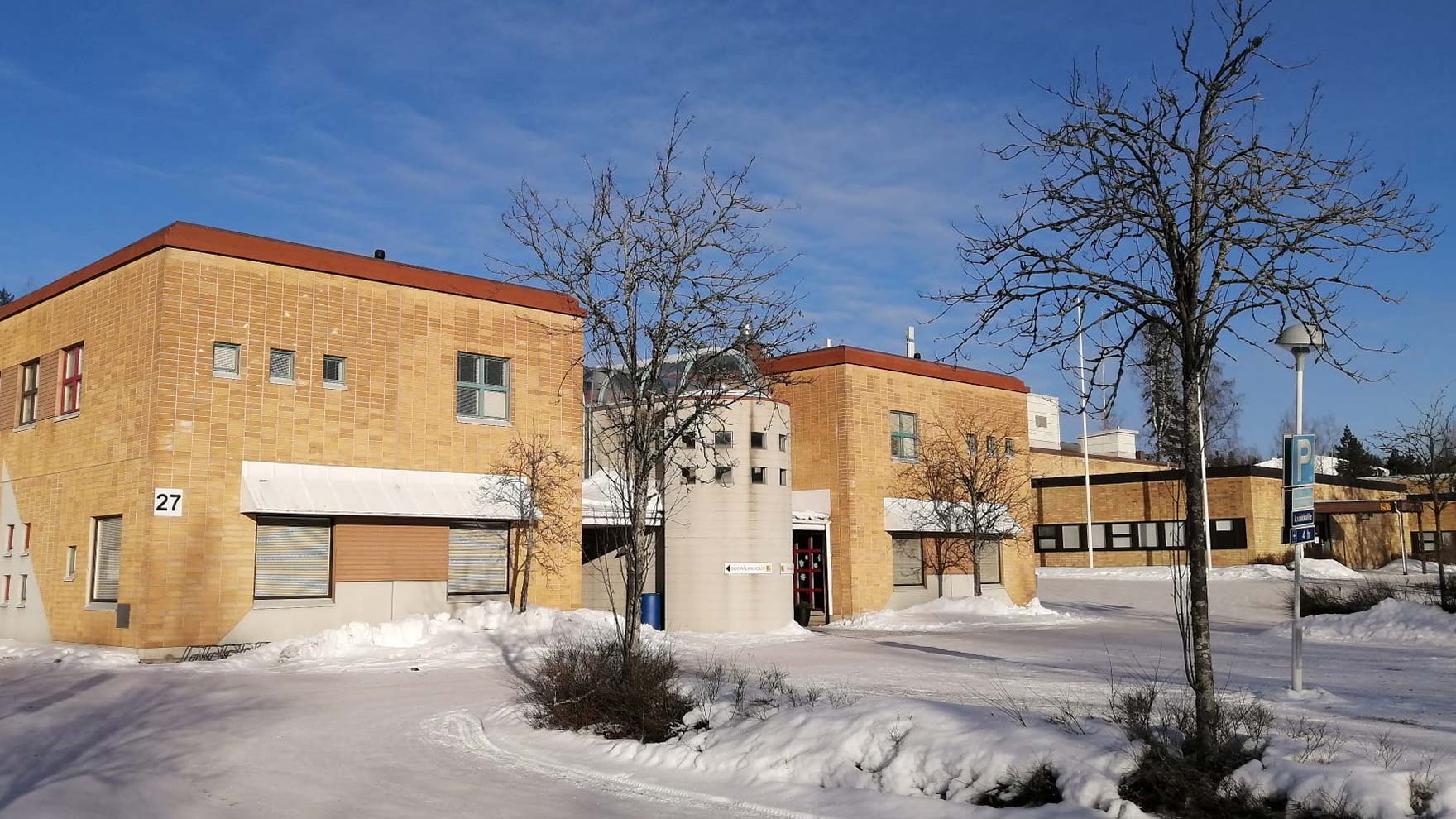 Talvinen kuva keltatiilisestä rakennuksesta.l