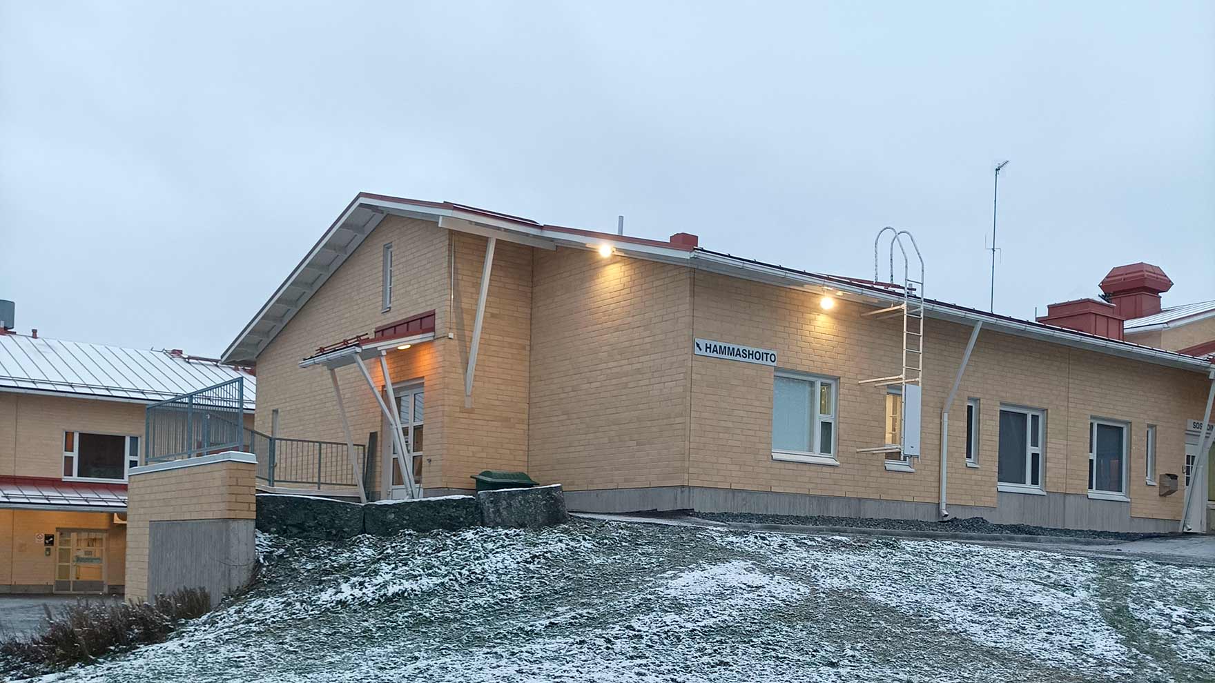 Keltainen tiilitalo mäen päällä.