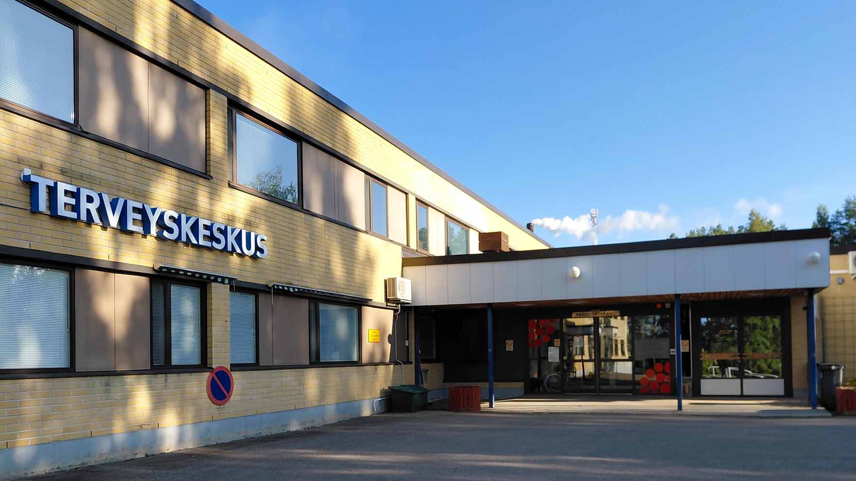 Kaksikerroksisen keltaisen tiilitalon sisäänkäynti, talon seinässä lukee Terveyskeskus.