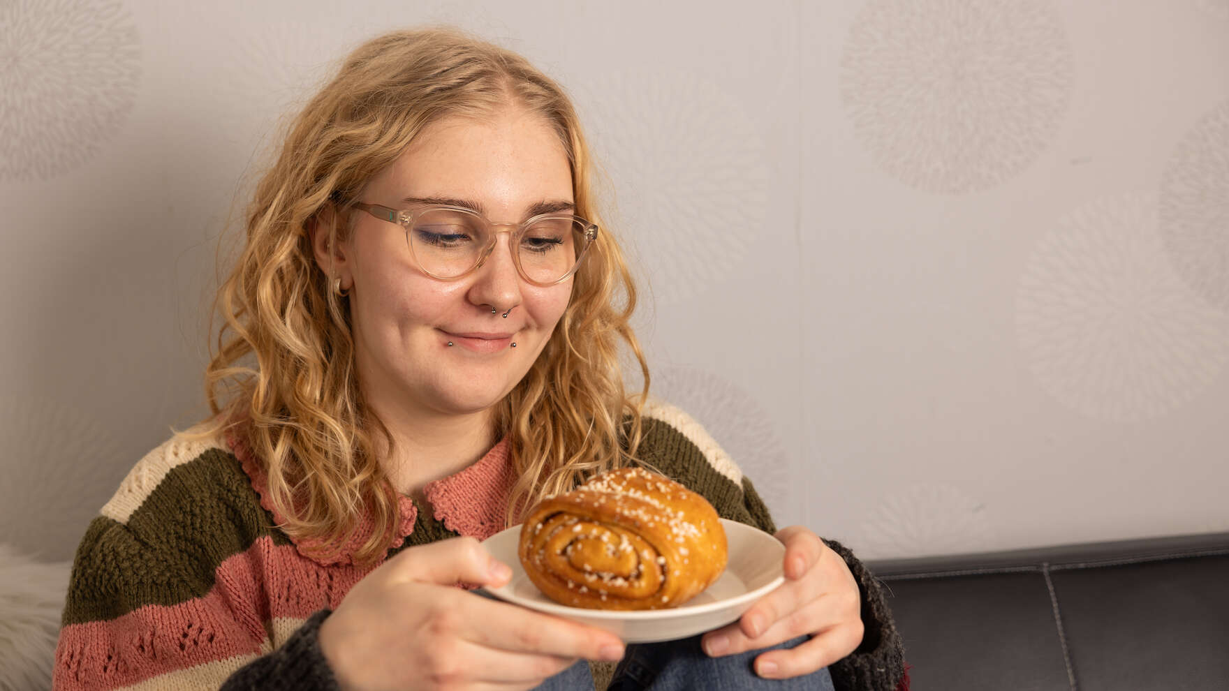 Kuvassa hymyilevä tyttö, jonka kädessä on korvapuusti.
